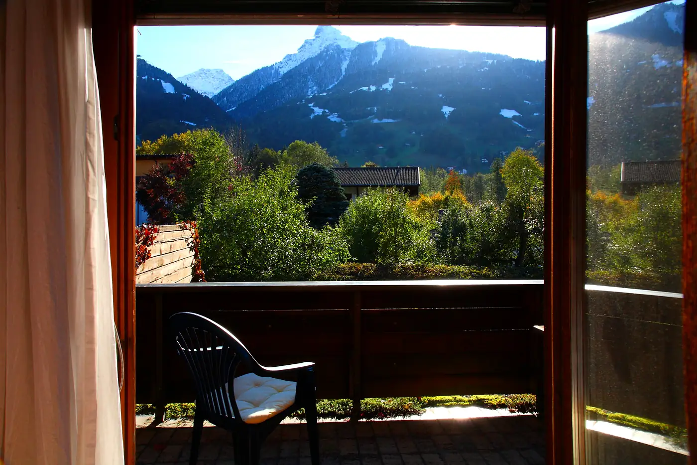 Blick vom Zimmerbalkon über den Garten auf die Berge